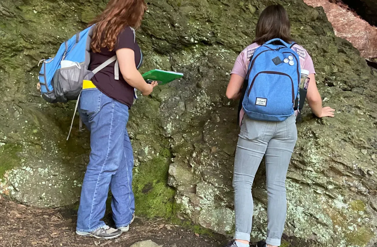 Two students inspecting rock surfaces.